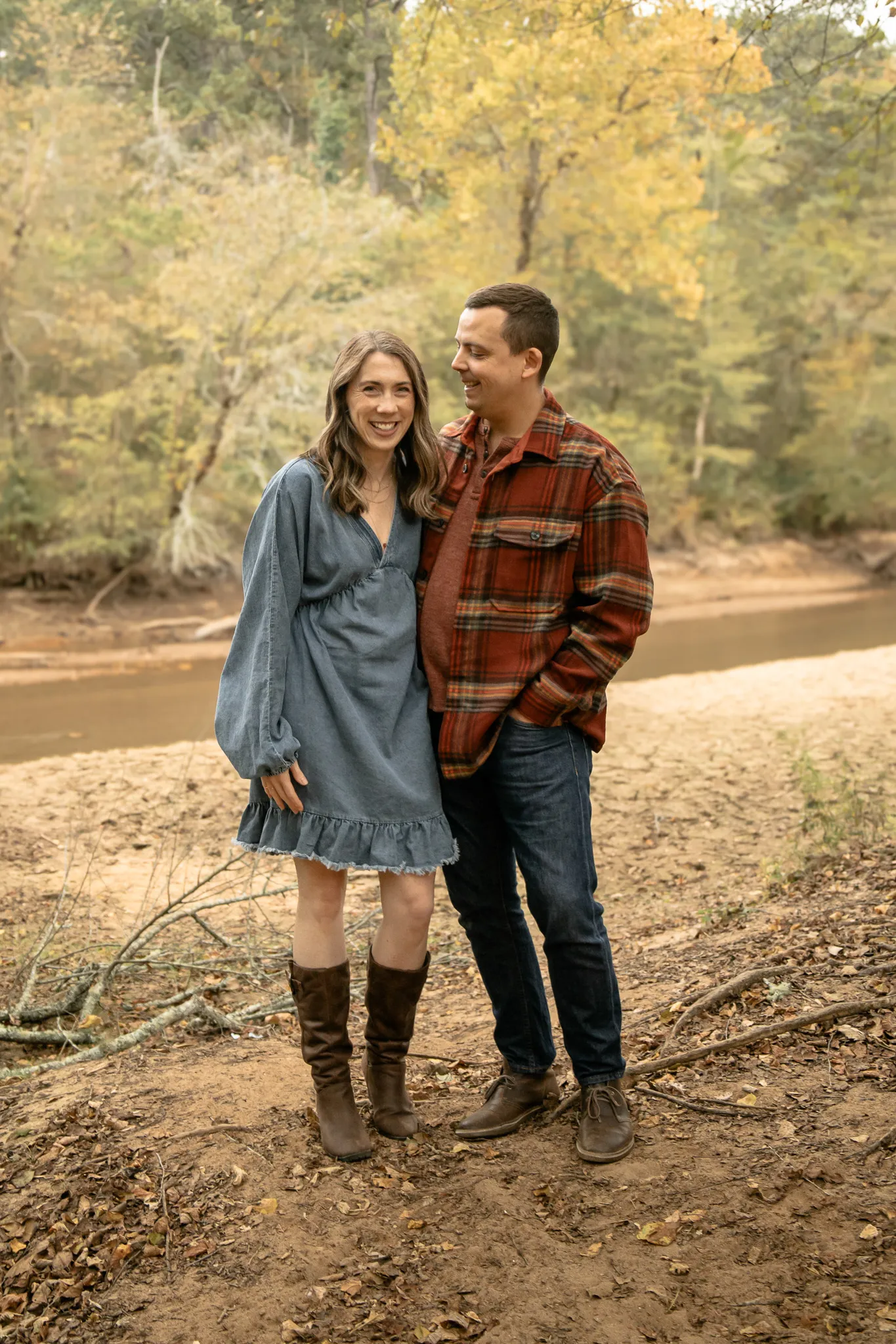Couple standing in front of a river laughing